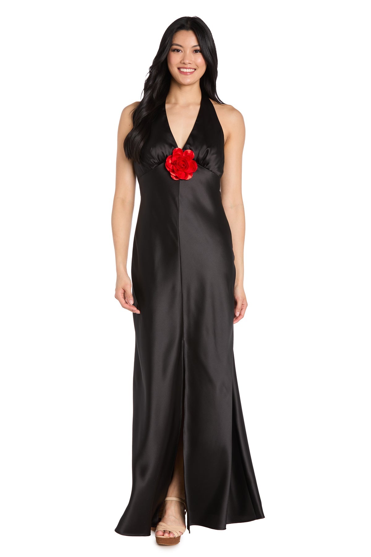 A woman in the R&M Richards 3773 Black Satin Halter Formal Dress with a red flower detail at the bodice smiles against a white background—ideal for any black-tie event.